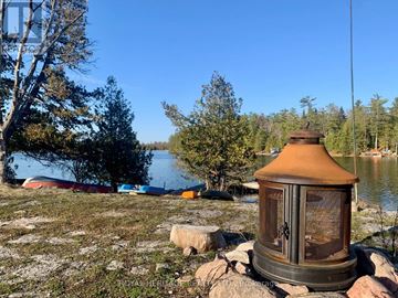 Kawartha Lakes (Verulam) apartment for rent - A rustic lantern sits on a rock by a lake with trees and boats in the background.