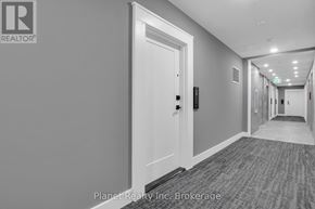 Guelph (St. Patrick's Ward) condo for rent - A hallway with a door on the left and a light switch on the wall.