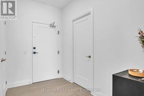 Guelph (St. Patrick's Ward) condo for rent - A room with two white doors and a wooden table with a plant on it.