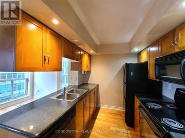 Toronto (Waterfront Communities) condo for rent - A kitchen with wooden cabinets and black appliances.