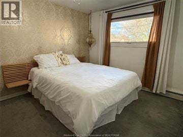 Windsor apartment for rent - A bedroom with a large bed and a window with curtains.