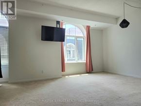 Toronto (Niagara) townhouse for rent - A room with a flat screen TV mounted on the wall and a window with red curtains.