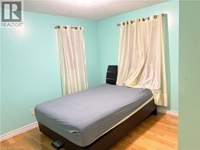 Kitchener apartment for rent - A bedroom with a bed, curtains, and a speaker.