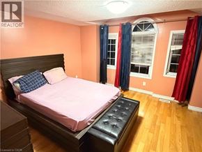 Kitchener apartment for rent - A bedroom with a pink bedspread and a black headboard.