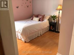 Arnprior apartment for rent - A bedroom with a bed, pillows, a lamp, and a plant.