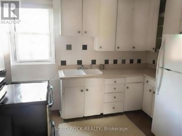 Arnprior apartment for rent - A kitchen with white cabinets and a black refrigerator.