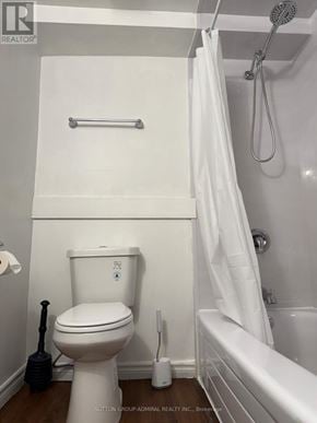 Barrie (Allandale) apartment for rent - A white toilet with a white shower curtain in a bathroom.