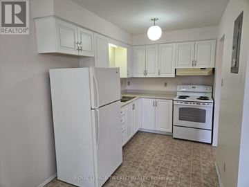St. Thomas fourplex for rent - A white refrigerator stands in a kitchen with white cabinets.