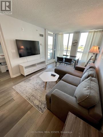 Toronto (West Humber-Clairville) condo for rent - A living room with a grey couch and a white entertainment unit.