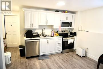 St. John's multi-family for rent - A kitchen with white cabinets and stainless steel appliances.