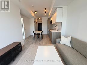 Toronto (Centennial Scarborough) condo for rent - A modern living room with a grey couch, a white table, and a kitchen area in the background.