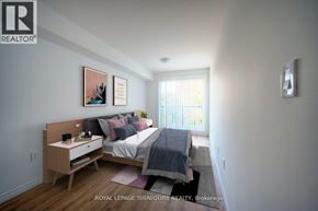 Kitchener condo for rent - A bedroom with a bed, nightstand, and two pictures on the wall.