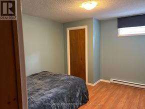 Alfred And Plantagenet apartment for rent - A bedroom with a bed, wooden door, and a window with blinds.