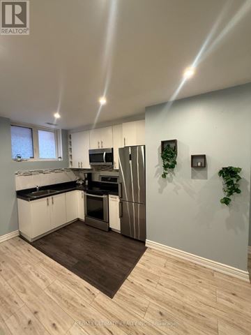 Toronto (Yorkdale-Glen Park) apartment for rent - A modern kitchen with a wooden floor and white walls.