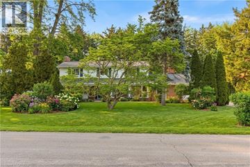 Oakville apartment for rent - A house with a green lawn and trees in front.