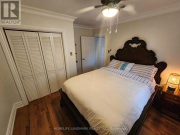 Toronto (The Beaches) triplex for rent - A bedroom with a large bed and a ceiling fan.