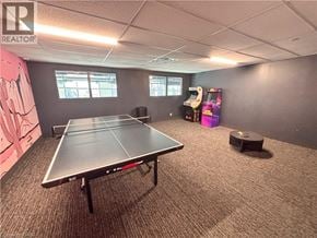 Kitchener condo for rent - A ping pong table is in the middle of a room with a realtor logo on the wall.