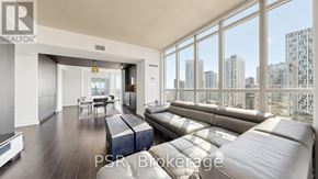 Toronto (Waterfront Communities) condo for rent - A living room with a large window overlooking a cityscape.