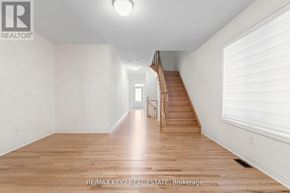Richmond Hill apartment for rent - A spacious room with wooden floors and a staircase leading to another room.