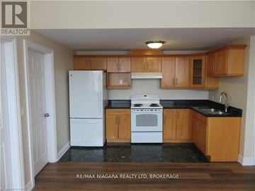 Fort Erie (Central) multi-family for rent - A kitchen with wooden cabinets and a white fridge.
