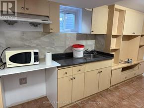 Toronto (L'amoreaux) apartment for rent - A kitchen with wooden cabinets and a black countertop.