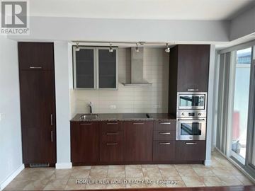 Toronto (Waterfront Communities) condo for rent - A kitchen with brown cabinets and a stainless steel oven.