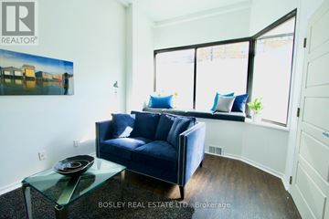 Toronto (Playter Estates-Danforth) duplex for rent - A living room with a blue couch and a glass table.