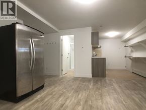 Burnaby apartment for rent - A spacious kitchen with a stainless steel refrigerator and wooden flooring.