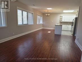 Toronto (Moss Park) apartment for rent - A large empty room with wood flooring and a kitchen in the background.