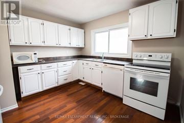 Welland (N. Welland) apartment for rent - A kitchen with white cabinets and a stove top oven.