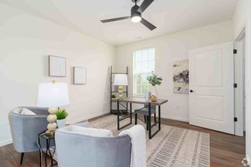 O'fallon apartment for rent - A living room with a grey couch, a table with a vase and a plant, and a ceiling fan.