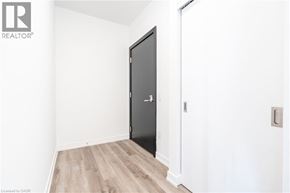 Kitchener condo for rent - A black door is in a white room with wood flooring.