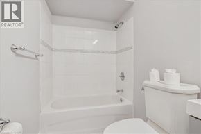 Hamilton apartment for rent - A white bathroom with a tub, toilet, and sink.