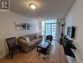 Toronto (Bay Street Corridor) condo for rent - A living room with a couch, chair, and a painting on the wall.