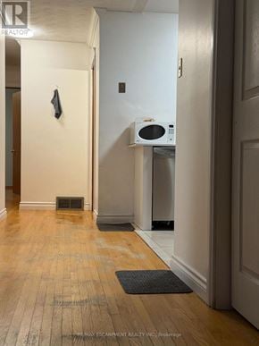 Hamilton (Kentley) apartment for rent - A hallway with a door on the right and a microwave on top of a dishwasher.