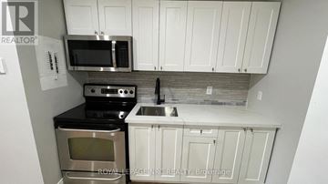 Welland (Welland Downtown) townhouse for rent - A kitchen with white cabinets and a black countertop.