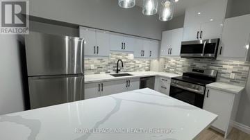 Welland (Welland Downtown) townhouse for rent - A modern kitchen with white cabinets and stainless steel appliances.