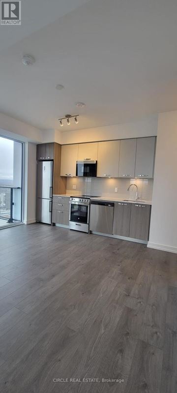 Hamilton (Corktown) condo for rent - A modern kitchen with wooden floors and stainless steel appliances.