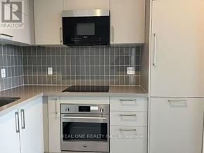 Markham (Unionville) condo for rent - A kitchen with a microwave above the stove and a brokerage sign on the wall.