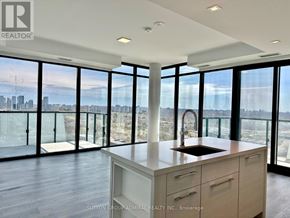 Toronto (Bayview Village) condo for rent - A modern kitchen with a view of the cityscape outside the large windows.