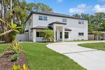 Sarasota apartment for rent - A white house with a black roof and a grey garage door.