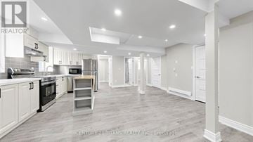 Kitchener apartment for rent - A spacious kitchen with white cabinets and a wooden floor.