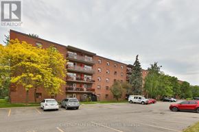 Oshawa (Lakeview) condo for rent - A parking lot with cars and a building in the background.