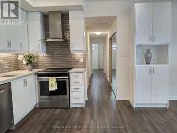 Mississauga (Mineola) townhouse for rent - A kitchen with white cabinets and a brick backsplash.