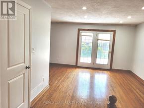Toronto (Bendale) apartment for rent - A room with wooden floors and a large window with a view of trees.