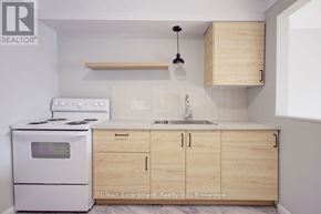 Burlington (Brant) multi-family for rent - A kitchen with a white stove and wooden cabinets.