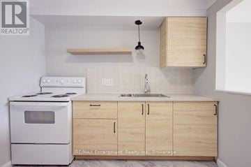 Burlington (Brant) multi-family for rent - A kitchen with a white stove and wooden cabinets.