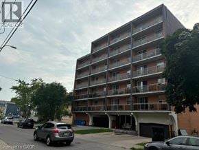Hamilton condo for rent - A multi-story apartment building with cars parked in front.