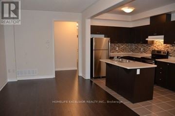 Markham townhouse for rent - A kitchen with dark brown cabinets and a stainless steel refrigerator.