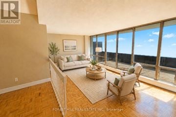 Toronto (York University Heights) house for rent - A living room with a couch, chair, and a small table with a plant on it.